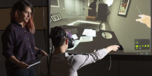 Fernanda Herrera, left, watches as fellow student Hannah Mieczkowski navigates through the VR experience that begins with an eviction notice. Herrera helped to conduct a two-month-long study of over 560 participants from the ages of 15 to 88.