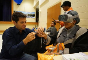 Climate researcher Juliano Calil helps a resident of Turner Station use the virtual reality program he created to show the expected impacts of sea level rise there.